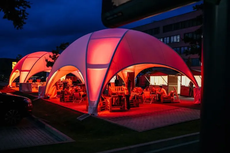 Two crossover domes side by side lit in warm red, with lounge seating underneath